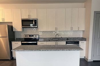 A kitchen with a granite countertop and white cabinets.